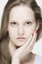 Portrait of young natural looking woman touching her face with her hand