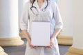 Portrait of a young nurse, medical university student standing with a phonendoscope and a blank sheet of paper, happy female