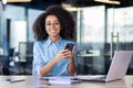 Portrait of young office worker with phone in hands, businesswoman smiling and looking at camera, using app on Royalty Free Stock Photo