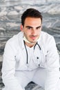 Portrait of young optimistic doctor who sitting on stairs