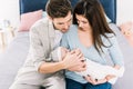 Portrait of young parents with cute baby sitting on bed Royalty Free Stock Photo