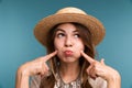 Portrait of a young pensive girl in summer hat isolated over blue background Royalty Free Stock Photo