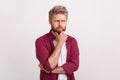 Portrait of young pensive man with beard touching chin and thinking about important question, making Royalty Free Stock Photo