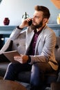 Portrait of young pensive businessman talking on cell phone in office Royalty Free Stock Photo