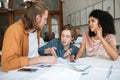 Young people emotionally discussing something in office. Two boys with blond hair and girl with dark curly hair sitting