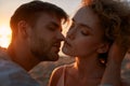 Portrait of young people in love looking passionate, kissing each other on the beach at sunset