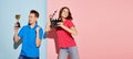 Portrait of young people, man with prize and woman with clapperboard isolated over blue-pink background. Flyer