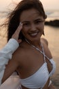 Portrait of young pleased Asian good-looking woman with long dark hair wearing white swimsuit, shirt, standing in water. Royalty Free Stock Photo