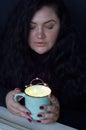 Portrait of young plus size woman with cup of magic luminous garland