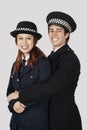 Portrait of young police officers embracing against gray background