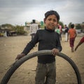 Portrait of young poor kid playing with bicycle wheel in India Royalty Free Stock Photo