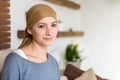 Portrait of young positive adult female cancer patient sitting in living room, smiling.