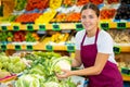 Portrait of young positive european woman working showing fresh cauliflower in store