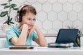 Portrait of young preteen interested boy looking at screen of tablet, having online lesson, listening, leaning on hands. Royalty Free Stock Photo