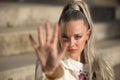 Portrait of a young, pretty, blonde woman with blue eyes, covering the camera with her hand as a sign of rejection and protest, Royalty Free Stock Photo