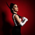 Portrait of young pretty brunette serious female in white gloves standing and holding asian dagger in hands Royalty Free Stock Photo