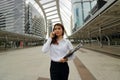 Portrait of young pretty business woman talking on phone at public outdoor background.