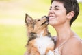 Portrait of young pretty caucasian woman enjoy and laugh while youth beautiful shetland dog puppy kiss her - concept of best Royalty Free Stock Photo
