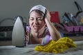 Portrait of young pretty frustrated and stressed Asian Chinese woman working at home kitchen ironing clothes desperate and overwhe