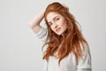 Portrait of young pretty ginger girl with freckles looking at camera smiling touching hair over white background. Royalty Free Stock Photo