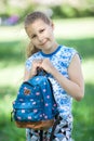 Portrait of young pretty girl cuddles bag to body, standing in summer park Royalty Free Stock Photo