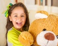 A portrait of a young pretty girl smiling and hugging her teddy bear over blurred background Royalty Free Stock Photo