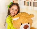 A portrait of a young pretty girl smiling and hugging her teddy bear over blurred background Royalty Free Stock Photo