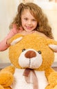 A portrait of a young pretty girl smiling and posing over her teddy bear s head in a doctor office background Royalty Free Stock Photo