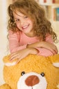 A portrait of a young pretty girl smiling and posing over her teddy bear s head in a doctor office background Royalty Free Stock Photo