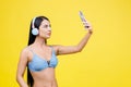 Portrait of young pretty girl with wireless headphones on head, taking selfie for social networks, smiling and laughing at phone Royalty Free Stock Photo