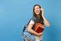 Portrait of young pretty laughing woman student in denim clothes with backpack headphones listening music holding school Royalty Free Stock Photo