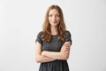 Portrait of young pretty positive girl smiling looking at camera with crossed arms over white background.