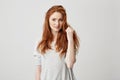 Portrait of young pretty redhead girl with freckles looking at camera smiling touching hair over white background. Royalty Free Stock Photo