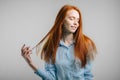 Young pretty redhead girl with freckles looking at camera smiling touching hair Royalty Free Stock Photo