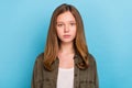 Portrait of young pretty serious looking teen girl wearing green shirt with long brown hair isolated on blue color Royalty Free Stock Photo