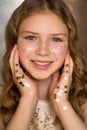 Portrait of young pretty teenager girl with golden freckles and star glitter on hands. Soft, selective focus. Royalty Free Stock Photo