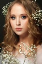 Portrait of young pretty woman with blonde curly hair and white flowers on head, beautiful face closeup