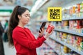 Portrait of a young, pretty woman scans the QR code on the yogurt package. A picture with a code is displayed above the product. Royalty Free Stock Photo