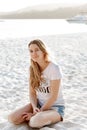 Portrait of young pretty woman sitting on the beach and looking at the camera Royalty Free Stock Photo