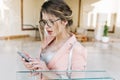 Portrait of young pretty woman, stylish business lady surprised looking at smartphone, holding silver phone in hands Royalty Free Stock Photo