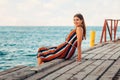 Portrait of a young, pretty woman was leaning against the wooden pier. In the background the sea. Concept of summer holiday. Copy Royalty Free Stock Photo