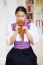 Portrait of young pretty woman wearing beautiful traditional andean clothing, sitting down with while playing the Royalty Free Stock Photo