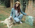 Portrait of young pretty 30 year old woman artist holding a picture and brushes and her pet dog Golden retriever lying Royalty Free Stock Photo