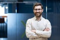 Portrait of a young programmer and engineer standing in the office with his arms crossed on his chest and smiling at the camera Royalty Free Stock Photo