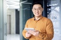 Portrait of young programmer with tablet computer inside office,asian man smiling and looking at camera, man at Royalty Free Stock Photo