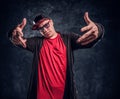 Portrait of a young rapper dressed in a hip-hop style, posing for a camera. Studio photo against a dark wall Royalty Free Stock Photo