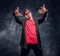 Portrait of a young rapper dressed in a hip-hop style, posing for a camera. Studio photo against a dark wall Royalty Free Stock Photo