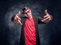 Portrait of a young rapper dressed in a hip-hop style, posing for a camera. Studio photo against a dark wall Royalty Free Stock Photo