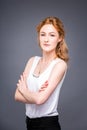 Portrait of a young redhaired beautiful girl in the studio on a gray isolated background. A woman is standing with her arms folded Royalty Free Stock Photo