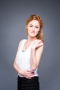 Portrait of a young redhaired beautiful girl in the studio on a gray isolated background. A woman is standing with her arms folded Royalty Free Stock Photo